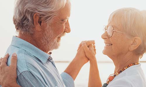 a happy retired couple dancing in the sunset